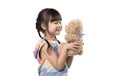 Cute little Asian girl hugging her favourite brown teddy bear and smiling in white background. Royalty Free Stock Photo