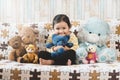 Cute little asian girl hugging her plush toy teddy bear on a sofa. Royalty Free Stock Photo