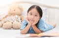 Cute little asian girl reading fairy tales book on bed Royalty Free Stock Photo