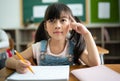 Cute little Asian girl sitting in a classroom and thinking about something at the elementary school. Education, school, Royalty Free Stock Photo