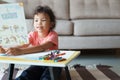 Cute little asian girl Sitting holding a drawing paper, drawing homework and writing with color Wax crayons on paper at living Royalty Free Stock Photo