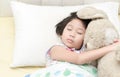 Cute little asian girl sleep and hug teddy bear on bed Royalty Free Stock Photo