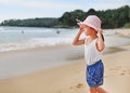 Cute little asian girl wear straw hat walking on the beach with looking out to the sea Royalty Free Stock Photo