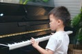 Cute little Asian kid boy concentrate on playing piano in living room at home, Preschool child having fun with learning to play Royalty Free Stock Photo