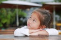 Cute little Asian kid girl with funny face lying on the wooden table with looking up Royalty Free Stock Photo