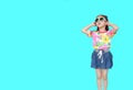 Cute little Asian kid girl wearing a flowers summer dress and sunglasses isolated on cyan background. Summer and fashion concept Royalty Free Stock Photo