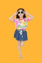 Cute little Asian kid girl wearing a flowers summer dress and sunglasses isolated on yellow background. Summer and fashion concept Royalty Free Stock Photo