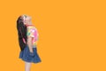 Cute little Asian kid girl wearing a flowers summer dress and sunglasses looking up isolated on orange background with copy space Royalty Free Stock Photo