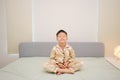 Asian boy child sitting on bed and practicing meditation in the morning after waking up in bedroom Royalty Free Stock Photo