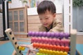 Cute asian kindergarten using the abacus with beads to learn how