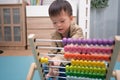 Cute asian kindergarten using the abacus with beads to learn how