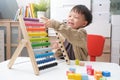 Cute little asian using the abacus with beads and wooden brick w