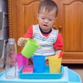 Asian 18 months old toddler boy child having fun pouring water into cup, Wet Pouring Montessori Preschool Practical Life Activitie