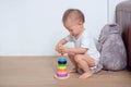 Cute little Asian 18 months / 1 year old toddler baby boy child play with colorful wooden pyramid toy / stacking ring to