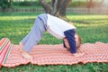 Cute little Asian 18 months / 1 year old toddler baby boy child practices yoga in Downward Facing Dog Pose and meditating outdoors