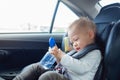 Cute little Asian 18 months / 1 year old toddler baby boy child sitting in car seat holding and drinking water from cup Royalty Free Stock Photo