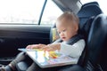 Cute little Asian 18 months / 1 year old toddler baby boy child sitting in car seat holding and enjoy reading book Royalty Free Stock Photo