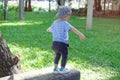 Cute little Asian 18 months / 1 year old toddler baby boy child walking on balance beam in the park on nature in summer,