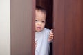 Cute little Asian 18 months / 1 year old toddler baby boy child wearing white sweater is hiding in the closet at home Royalty Free Stock Photo