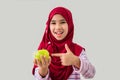 Cute little Asian Muslim girl wearing headscarf holding green apple fruit in her hand happiness on white background