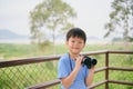 Cute little Asian school boy child looking through binoculars explores nature field at viewpoint outdoors Royalty Free Stock Photo