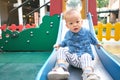Cute little Asian toddler baby boy child playing on a slide in playground on summer sunny day Royalty Free Stock Photo