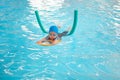 Cute little Asian toddler boy child kicking feet in swimming costume wear swimming goggles use pool noodle and kickboard learn to