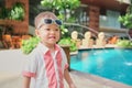 Cute little Asian toddler boy child with sunglasses wearing stylish shirt smiling near the pool at hotel in the summer outdoors Royalty Free Stock Photo