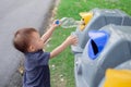 Cute little Asian toddler boy child throwing plastic bottle in recycling trash bin at public park Royalty Free Stock Photo