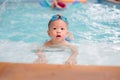 Cute little Asian 18 months toddler boy child in trunks wear swimming goggles learn to swim at indoor pool Royalty Free Stock Photo