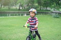 Cute little Asian toddler boy child wearing safety helmet learning to ride first balance bike in sunny summer day, kid playing & Royalty Free Stock Photo