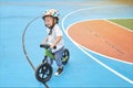 Cute little Asian toddler boy child wearing safety helmet learning to ride his first balance bike, kid playing & cycling at the Royalty Free Stock Photo