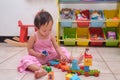 Cute little Asian toddler girl child having fun playing with plastic toy blocks on floor at home Royalty Free Stock Photo