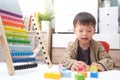 Cute little asian using the abacus with beads and wooden brick with numbers to learn how to count at home, Use an Abacus to teach