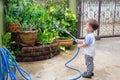 Cute little Asian 2 year old toddler baby boy child having fun watering the plants from hose spray in the garden at home Royalty Free Stock Photo