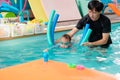 Cute little Asian 2 year old toddler boy child wear swimming goggles learning to swim with pool noodle at indoor pool Royalty Free Stock Photo