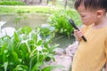 Asian 3 - 4 years old toddler baby boy child exploring environment by looking through a magnifying glass in sunny day at beautiful