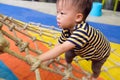 Asian 2 years old toddler baby boy child having fun trying to climb on jungle gym at indoor playground Royalty Free Stock Photo