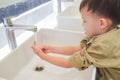 Sian 3 - 4 years old toddler baby boy child washing hands by himself on sink and water drop from faucet in public toilet Royalty Free Stock Photo