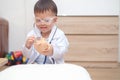 Asian 2 - 3 years old toddler boy child in doctor uniform playing doctor with plush toy at home Royalty Free Stock Photo