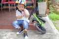 Asian 2 years old toddler boy child getting ready for cycle by wearing, fitting bicycle helmet before riding balance bike Royalty Free Stock Photo