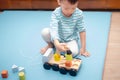 Asian 3 - 4 years old toddler boy child having fun playing with wooden building blocks and loader car toys indoor at nursery / Royalty Free Stock Photo
