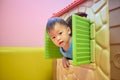 Asian 2 years old toddler boy child is playing peek a boo from the window of plastic toy house, Kids indoor playground, Indoor Royalty Free Stock Photo