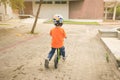 Asian toddler boy child wearing safety helmet learning to ride first balance bike on cement floor Royalty Free Stock Photo