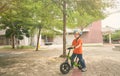 Asian toddler boy child wearing safety helmet learning to ride first balance bike on cement floor Royalty Free Stock Photo