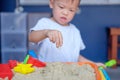Asian 2 years old toddler boy playing with kinetic sand in sandbox at home Royalty Free Stock Photo