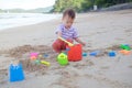 Cute little Asian 2 years old toddler boy sitting & playing children`s beach toys on beautiful sandy tropical beach Royalty Free Stock Photo