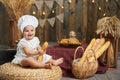 Cute little baby baker with a French baguette in a rustic wooden interior