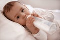 Cute little baby with bottle lying in comfortable crib Royalty Free Stock Photo