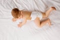 Cute little baby boy, child in diaper lying on bed, crawling, playing  over white studio background Royalty Free Stock Photo